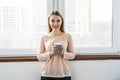 Young woman sitting on the windowsill and looking out the window with cup of coffee in the morning Royalty Free Stock Photo