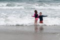 Young cute little boy and girl playing at the seaside running into the surf on a sandy beach in summer sunshine Royalty Free Stock Photo