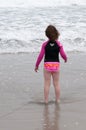 Young cute little girl playing at the seaside running into the surf on a sandy beach in summer sunshine Royalty Free Stock Photo