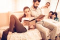 Young Cute Parents Reading Book while Kids Playing Royalty Free Stock Photo