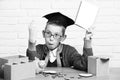 Young cute pupil boy in grey sweater and glasses sitting at desk with copybook in hand wooden numbers pink piggy pig Royalty Free Stock Photo