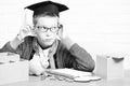 Young cute pupil boy in grey sweater and glasses sitting at desk with copybook wooden numbers pink piggy pig bank in Royalty Free Stock Photo