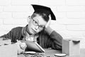 Young cute pupil boy in grey sweater and glasses sitting at desk with copybook wooden numbers pink piggy pig bank in Royalty Free Stock Photo