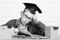 Young cute pupil boy in grey sweater and glasses sitting at desk with copybook wooden numbers pink piggy pig bank in Royalty Free Stock Photo