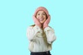 Young cute red-haired teen girl in a knitted pink hat and mittens hugging her cheeks with cute smiles with her hands Royalty Free Stock Photo