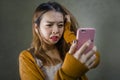 Young cute and sad Asian Korean girl feeling broken heart and desperate holding mobile phone suffering relationship break up Royalty Free Stock Photo