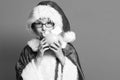 Young cute santa claus boy with glasses in xmas sweater and new year christmas hat holding and kissing pink piggy pig Royalty Free Stock Photo