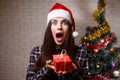 Young cute surprised excited woman in Santa cap is amazed by a p Royalty Free Stock Photo