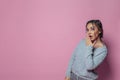 Young cute surprised woman with opened mouth on vivid pink studio wall banner background