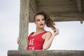 Young cute woman in red monokini on a wooden lifeguard tower