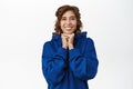 Young cute woman, girlfriend looking with love and tenderness at something adorable, standing in blue hoodie over white