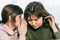 Young cute woman whispering secret on ear to her female friend. Communication and surprised girl by gossip Royalty Free Stock Photo