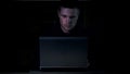 Young cyber criminal braking system security sitting laptop, virtual virus code