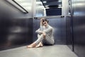 Young cyber woman in silver futuristic costume sitting in the elevator.