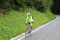 Cyclist climbs the tiring road in with rain gear during a rainy