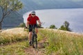 Young cyclist cycling in the green summer meadow against beautiful landscape. Royalty Free Stock Photo