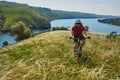 Young cyclist cycling in the green summer meadow against beautiful landscape. Royalty Free Stock Photo