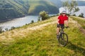 Young cyclist cycling in the green summer meadow against beautiful landscape. Royalty Free Stock Photo