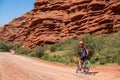 Young cyclist on gravel road with red eroded mountains background. Leisure, travel, recreation concept