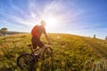 Young cyclist with mountain bicyclist on the path of the field in the countryside against sunrise. Royalty Free Stock Photo