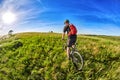 Young cyclist riding mountain bicycle through green meadow against beautiful sky. Royalty Free Stock Photo