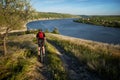 Young cyclist riding mountain bike uphill along a country road above river. Royalty Free Stock Photo