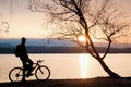 Young cyclist silhouette on blue sky and sunset background on beach. End of season at lake. Royalty Free Stock Photo