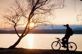 Young cyclist silhouette on blue sky and sunset background on beach. End of season at lake. Royalty Free Stock Photo