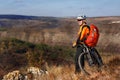 Young cyclist stands with the mountain bike on the summer rocky trail against beautiful landscape with mountain. Royalty Free Stock Photo