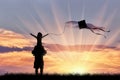 Young dad with child playing with kite sunset