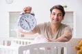 The young dad with clock near newborn baby bed cot Royalty Free Stock Photo