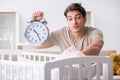 The young dad with clock near newborn baby bed cot Royalty Free Stock Photo