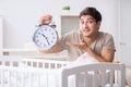 The young dad with clock near newborn baby bed cot Royalty Free Stock Photo