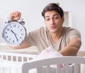 Young dad with clock near newborn baby bed cot Royalty Free Stock Photo