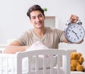 The young dad with clock near newborn baby bed cot Royalty Free Stock Photo