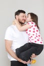 young dad holds his little daughter in his hands. father hugging his child with love and child kiss him. man in white t Royalty Free Stock Photo