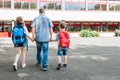 A young dad leads his children by the hand with backpacks on their backs to school. Back to school. Beginning of the