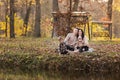 Young dad and mom with baby girl and little son having fun on blanket near pond in autumn park on sunny day. happy family concept Royalty Free Stock Photo