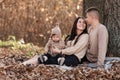 Young dad and mom with baby girl relaxing on blanket in autumn park on sunny day. happy family concept. mother`s, father`s, baby Royalty Free Stock Photo