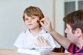 Young dad painting flag on face of little son for football or soccer game. Happy excited preschool kid boy fan and