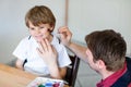 Young dad painting flag on face of little son for football or soccer game. Happy excited preschool kid boy fan and