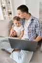 Young dad sitting on sofa at home with kid watching educational classes on pc. Royalty Free Stock Photo