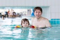 Young dad teaching his little son to swim indoors Royalty Free Stock Photo