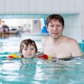 Young dad teaching his little son to swim indoors Royalty Free Stock Photo