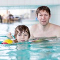 Young dad teaching his little son to swim indoors Royalty Free Stock Photo