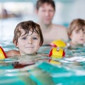 Young dad teaching his two little sons to swim indoors Royalty Free Stock Photo