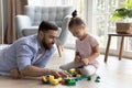 Young daddy and cute little daughter build together with blocks