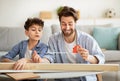 Young daddy and his teen son measuring wooden plank with tape ruler, man teaching boy doing housework