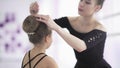 Young dance teacher fixing hairstyle to her student