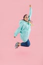 Young dancer woman in oversize clothes jumping on pink isolated studio background Royalty Free Stock Photo